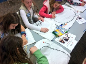A Girl Scout troop colors preparedness kits during a Red Cross Pillowcase Project session.